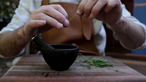 Man-preparing-herbs-for-cooking-with-a-pestle-and-mortar