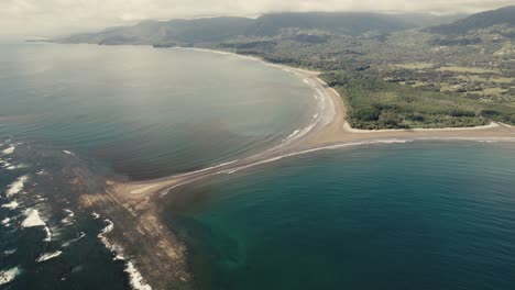 drone-over-whale-tail-shaped-coastline-in-Costa-Rica-national-park-with-long-waves