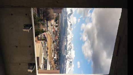 Industrial-construction-window-mountains-and-city-vertical-time-lapse-sunny-weather