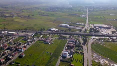 Top-drone-view-of-a-agricultural-field-close-to-the-highway-in-the-charming-town-of-chalco-Mexico,-and-view-of-the-downtown-and-roads-towards-Mexico-City