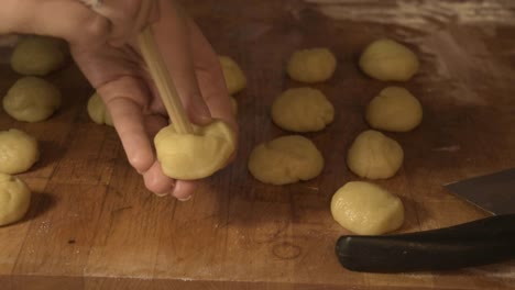 Making-holes-with-the-wooden-spoon-in-the-cookie-dough-balls,-on-the-cutting-board
