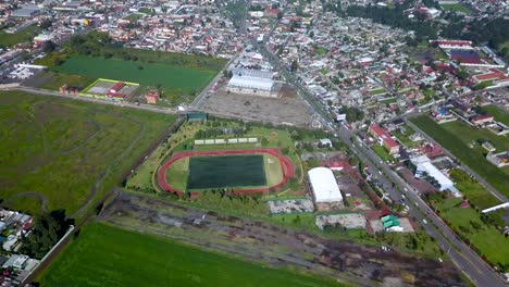 Top-drone-view-of-a-soccer-field-in-the-charming-town-of-chalco-Mexico,-and-view-of-the-town-and-houses