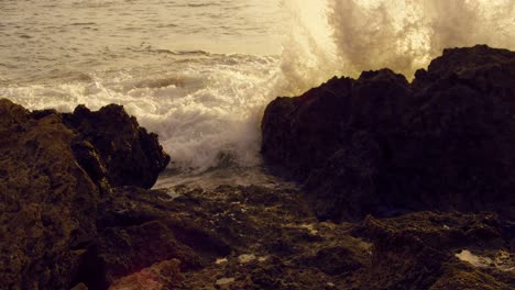 Majestic-Slow-Motion-Ocean-Waves-Crash-on-Sharp-Rocks-during-Golden-Hour,-Low-Angle,-Static
