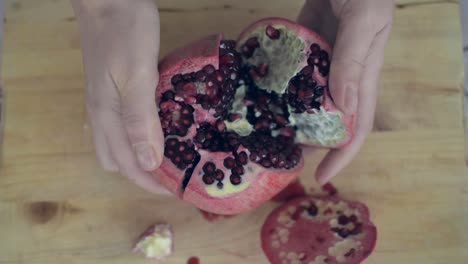Opening-a-sliced-pomegranate-with-hands,-easily
