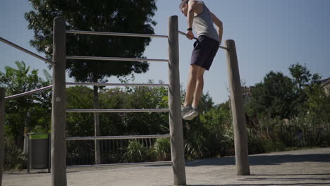 A-man-pulls-himself-up-onto-a-pull-up-bar-in-slow-motion-during-a-workout-in-a-park