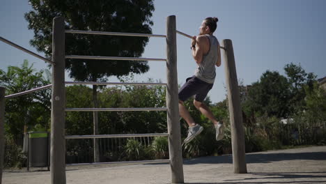 Man-performing-a-slow-motion-pull-up-from-behind-during-a-workout-in-a-park