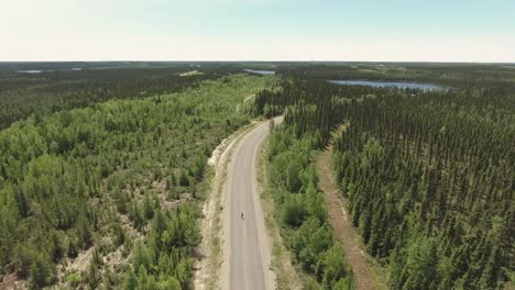 Ein-Typ-Fährt-Longboard-Auf-Einer-Einsamen-Straße-In-Einem-Großen-Kanadischen-Wald