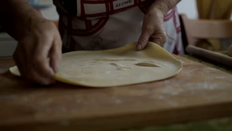 Italian-woman-making-a-very-thin-sheet-of-dough-before-cutting-pasta