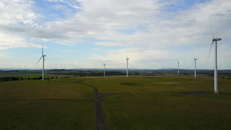 Luftaufnahmen-Von-Drohnen-Eines-Windparks,-Der-Sich-Langsam-Auf-Turbinen-Zubewegt,-Mit-Blauem-Himmel-Und-Wolken-über-Ackerland