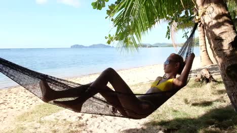 Young-asian-girl,-relaxes-in-a-hammock-on-the-beach