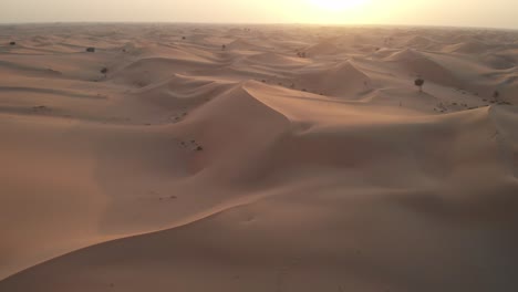 Drone-flying-towards-the-sunset-in-Abu-Dhabi-desert,-United-Arab-Emirates