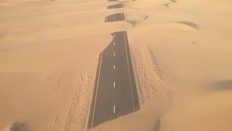 Vista-Aérea-Desde-Drones-De-Carreteras-Abandonadas-Del-Desierto-Cubiertas-De-Dunas-De-Arena-En-Dubai,-Emiratos-árabes-Unidos