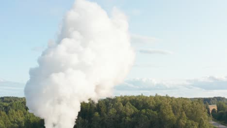 Aerial-drone-shot-of-a-factory-chimney-spewing-fumes-into-atmosphere-in-rural-area