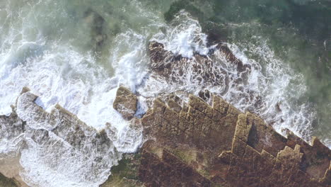 White-waves-crashing-onto-horizontal-bedded-sedimentary-ocean-rocks-aerial-view-Turimetta-Beach-Sydney-Australia
