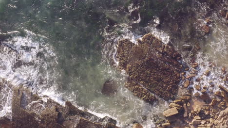 Weiße-Wellen-Rollen-Auf-Mit-Algen-Bedeckten-Horizontal-Gebetteten-Sedimentgesteinen-Ozean-Felsen-Luftaufnahme-Langsame-Schwenk-Rechts-Nach-Links-Felsige-Küstenlinie-Turimetta-Beach-Sydney-Australien