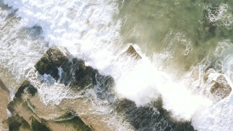 White-waves-rolling-up-onto-seaweed-covered-horizontal-bedded-sedimentary-ocean-rocks-aerial-view-Turimetta-Beach-Sydney-Australia