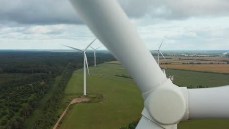 Close-up-of-a-rotating-wind-turbine-with-turbine-park-in-background