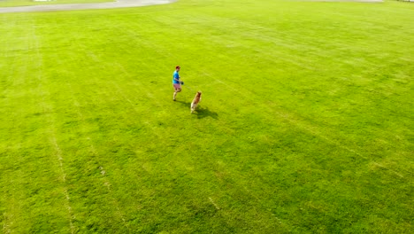 Man-running-freely-through-grass-field-with-dog