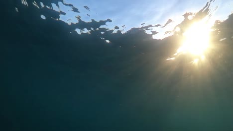 Slow-motion-underwater-footage-of-boat-hull-passing-very-close-with-sunlight-shining-through-water
