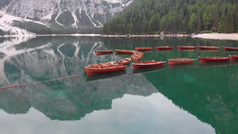 Aerial-shot-from-drone-around-aligned-boats-in-Braies-lake-in-the-Dolomites,-Italy
