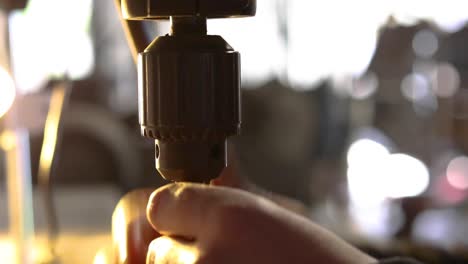 Close-up-of-man's-hand's-putting-drill-bit-into-drill-press-and-then-tightening-by-and-then-with-a-chuck-key