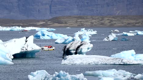 Un-Pequeño-Barco-Turístico-Pasa-Cerca-De-Unos-Enormes-Icebergs