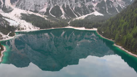 Aerial-drone-shot-over-lake-Braies-revealing-the-beautiful-nature-around-it,-Dolomites-Italy