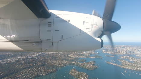 Small-commuter-aircraft-flying-over-Sydney-Harbour-with-Sydney-Harbour-bridge-in-background