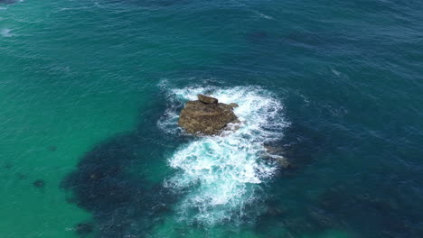 Aerial-drone-view-of-waves-crashing-against-a-rock-in-the-sea-in-st-ives-Cornwall