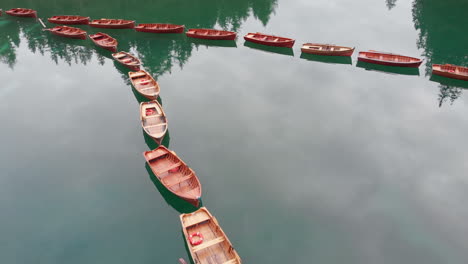 Aerial-shot-from-drone-over-aligned-boats-in-Braies-lake-in-the-Dolomites,-Italy