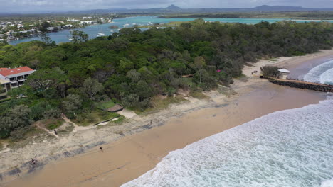 Aerial-footage-along-the-beach-at-Noosa-flying-over-the-lifeguard-station-and-wave-breaker