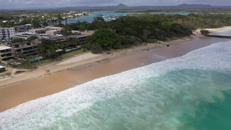 Noosa-beach-aerial-shot-with-lifeguard-buggy-and-walkers-and-the-sea-rolling-in