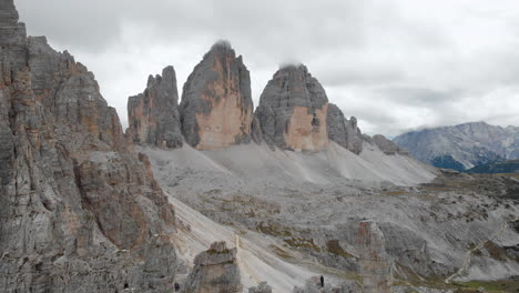 Aerial-shot-from-a-drone-over-a-male-model-looking-at-Tre-Cime-di-Lavaredo-in-the-Dolomites,-Italy