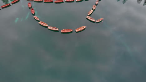 Aerial-backwards-shot-from-a-drone-revealing-aligned-boats-in-Braies-lake-in-the-Dolomites,-Italy