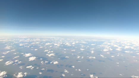 POV-Aus-Dem-Flugzeugfenster,-Das-Von-Darwin-Northern-Territory-Fliegt-Und-Einen-Gebogenen-Horizont-Zeigt,-Weiße-Wolken,-Die-Schatten-Auf-Die-Rote-Erde-Im-Outback-Australiens-Werfen