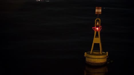 Gelbe-Meeresboje-Mit-Rotem-Licht,-Das-Nachts-Auf-Dem-Wasser-Schwimmt
