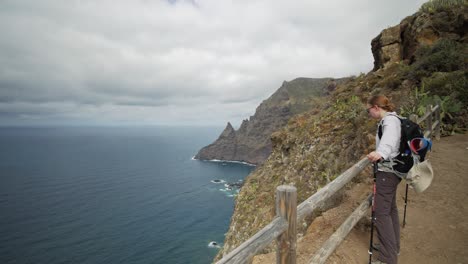 Female-hiker-enjoys-panoramic-view-over-the-ocean-in-Anga-mountains-on-Tenerife,-Spain