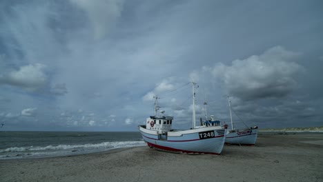 Timelapse-of-clouds-moving-over-two-fisherman-boats-on-a-beach