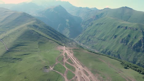 Aerial-view-from-drone-of-cars-driving-through-mountain-paths-in-Gergeti,-Georgia