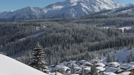 Panoramic-view-over-a-village-in-winter-with-snow-covered-houses,-trees-and-mountains