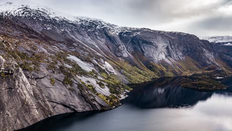 Mountains-rising-from-the-dark,-calm,-mirror-like-waters-of-the-Andkjelvatnet-lake