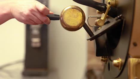 Die-Hände-Der-Frau-öffnen-Die-Kaffeeröstmaschine,-Um-Frisch-Geröstete-Kaffeebohnen-Freizugeben