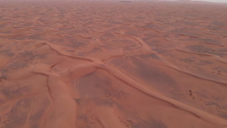 Flying-forward-aerial-shot-of-arabian-red-desert-dunes-at-sunset-in-Dubai,-United-Arab-Emirates