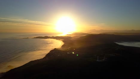 Goldener-Stundensonnenuntergang-über-Der-Südafrikanischen-Küste,-Rückwärtsbewegung-Der-Luftdrohne-Mit-Linsenblendung