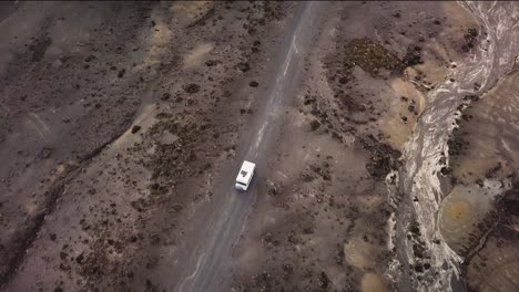 An-old-camper-van-drives-through-the-desert-at-Tukino-Access-Road,-Tongariro-National-Park---Rangipo-Desert