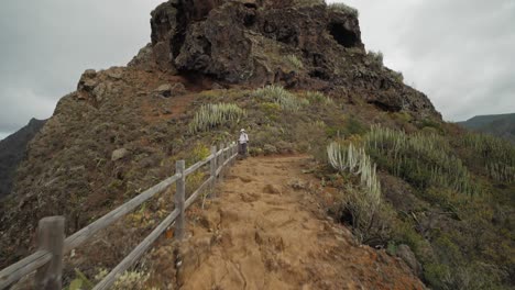 Walking-towards-a-femal-hiker-enjoying-the-view-on-a-ridge-in-Anaga-mountains-on-Tenerife,-Spain