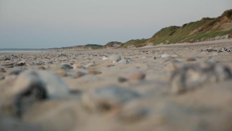 Steine,-Die-An-Einem-Strand-Liegen,-Wobei-Der-Fokus-Von-Steinen-Auf-Den-Hintergrund-Gezogen-Wurde