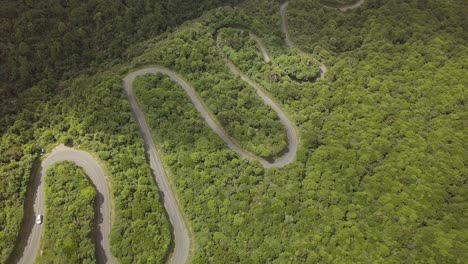 Aerial-overhead-shot-over-a-lonely-serpentine-road-at-Egmont-National-Park,-North-Island,-New-Zealand