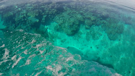Moving-Past-Coral-Reef-Head-Below,Clear-Blue-Water,-Boat-Wake-HANDHELD