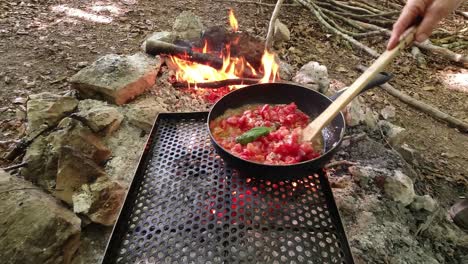 Cooking-the-italian-delicious-tomato-and-meat-sause,-sugo,-in-the-woods-on-the-wildfire